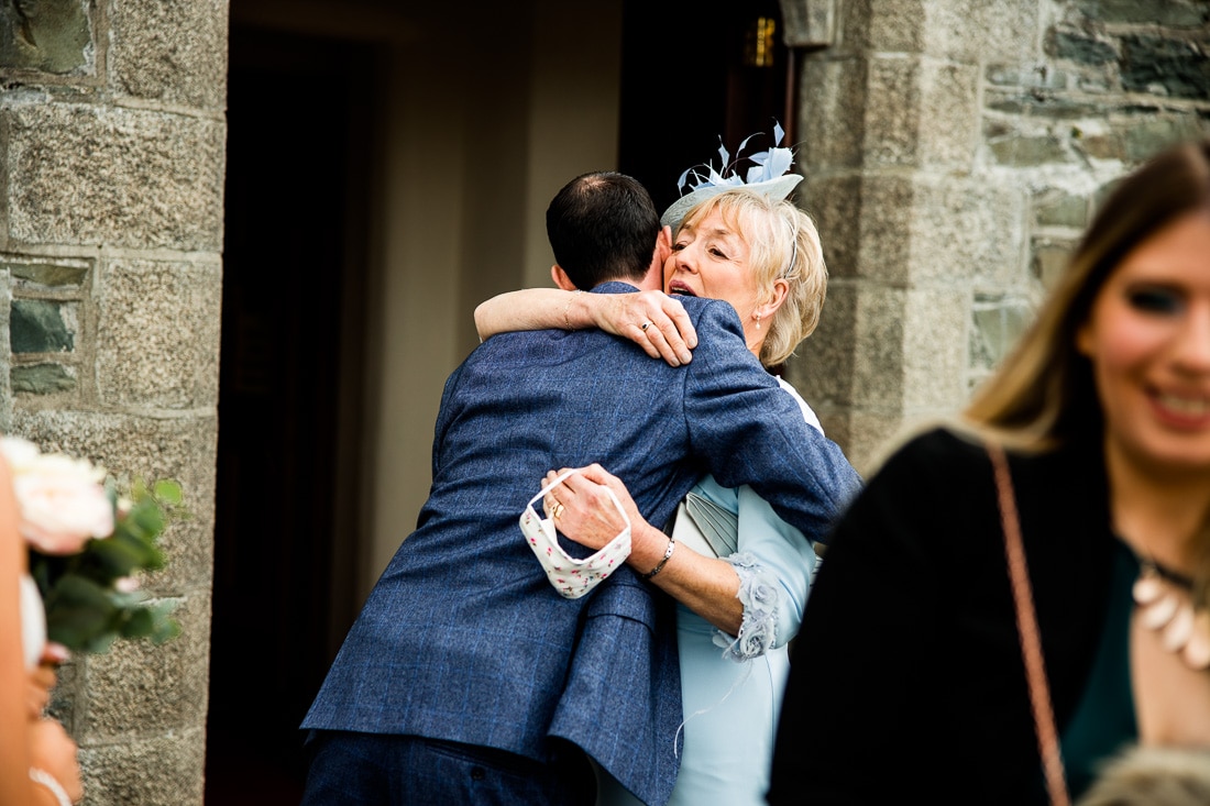 a wedding guest hugs the groom after the ceremony