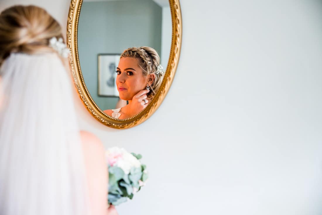 bride looking in a mirror adjusting her earring
