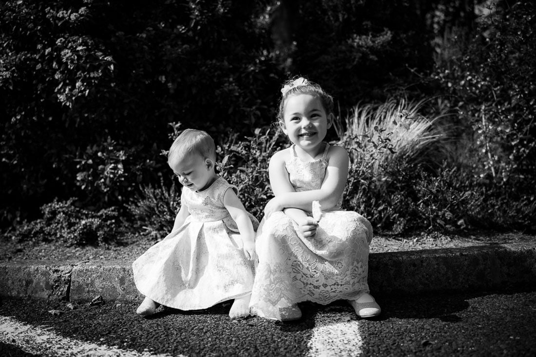 tow flower girls sit on the bench outside a church