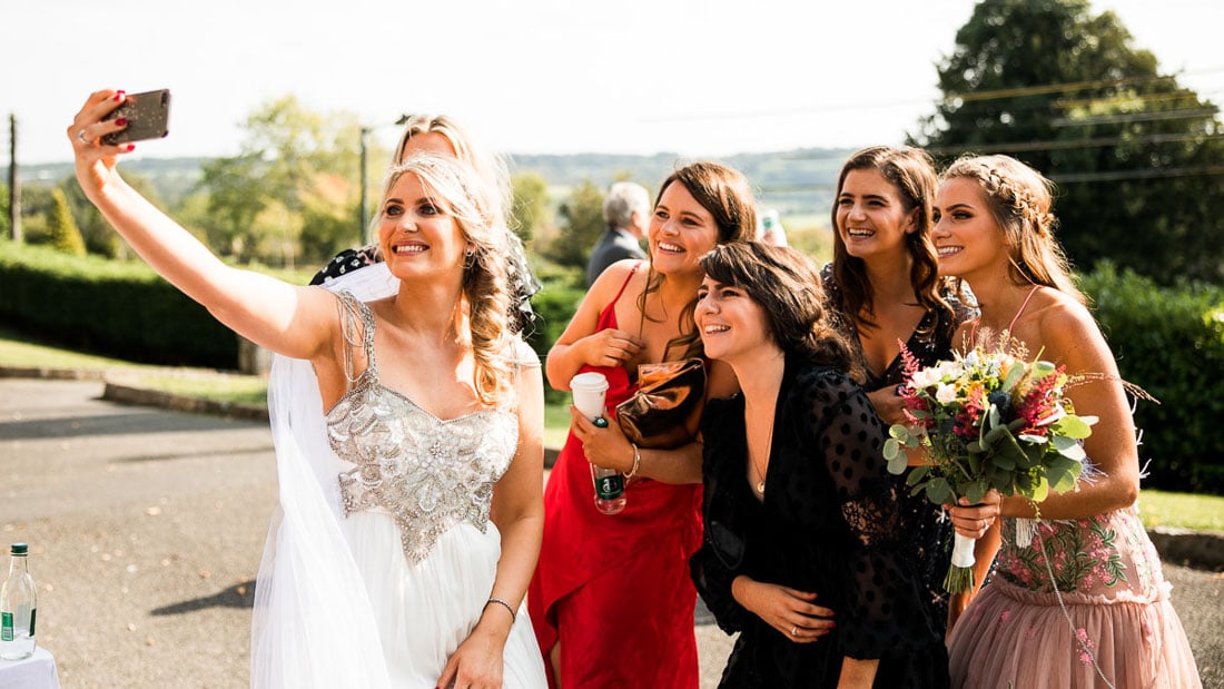 bride and her friends take a selfie outside the church