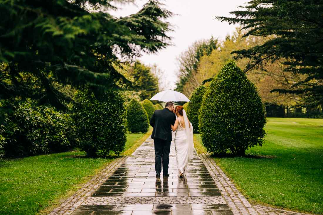 bride and groom walking in moyvalley house gardens in the rain