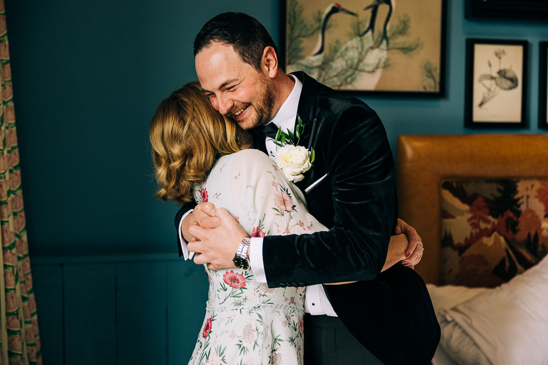 Groom hugs his mum after she pins his flower to his jacket