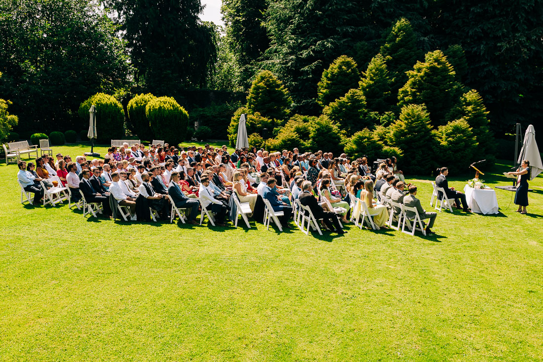 rathsallagh-house-wedding-jess-5 Wedding guests seated on white chairs for an outdoor ceremony on the sunny lawn at Rathsallagh House
