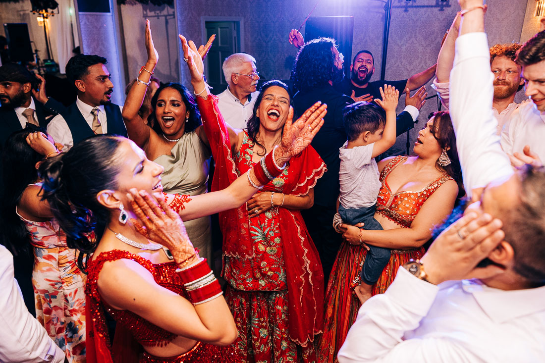 rathsallagh-house-wedding-jess-8 Bride in a red lehenga dancing joyfully with wedding guests at the Rathsallagh House reception