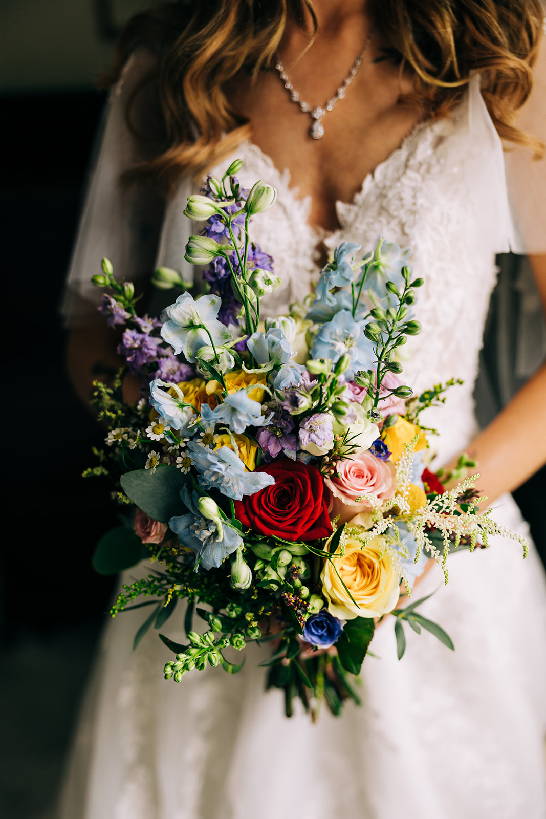 Magdalena & Ronan | Martinstown House close up of the brides colourful wildflower bridal bouquet with red yellow and blue flowers