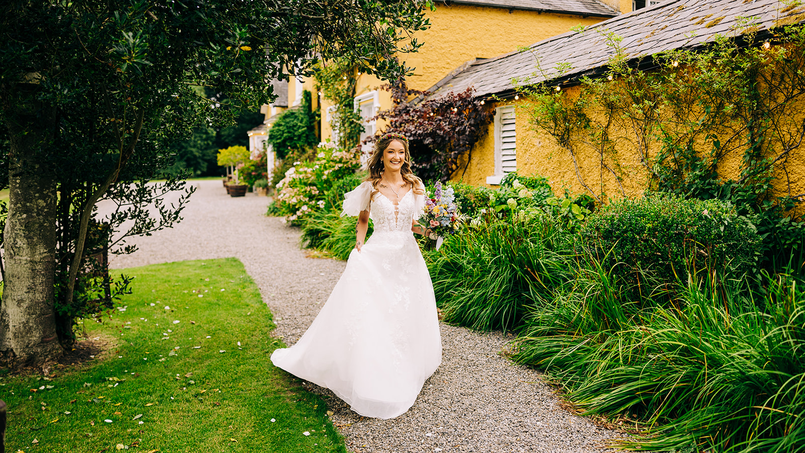 Magdalena & Ronan | Martinstown House bride smiling and walking through the lush garden path beside Martinstown House Ireland dress flowing in the breeze