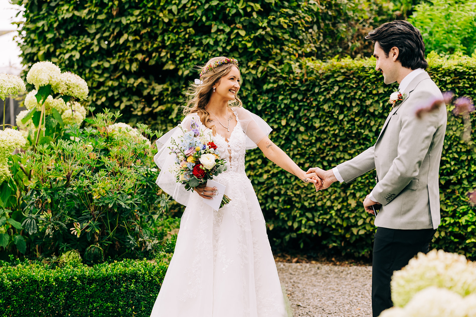 Magdalena & Ronan | Martinstown House bride and groom holding hands and smiling at each other among the hydrangeas and box hedging in the walled garden at Martinstown House
