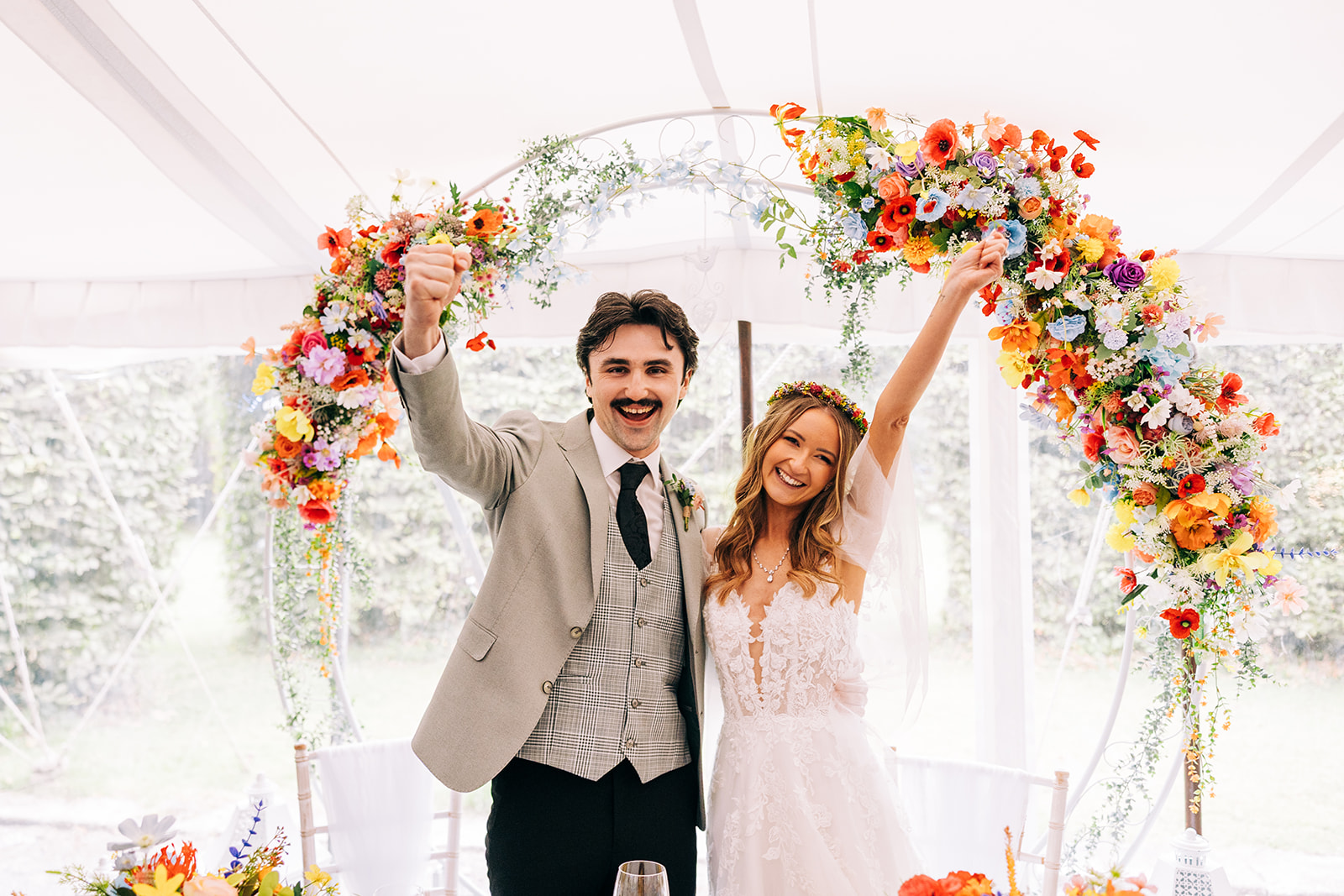 Magdalena & Ronan | Martinstown House bride and groom triumphantly raising their arms inside the floral decorated marquee at Martinstown House