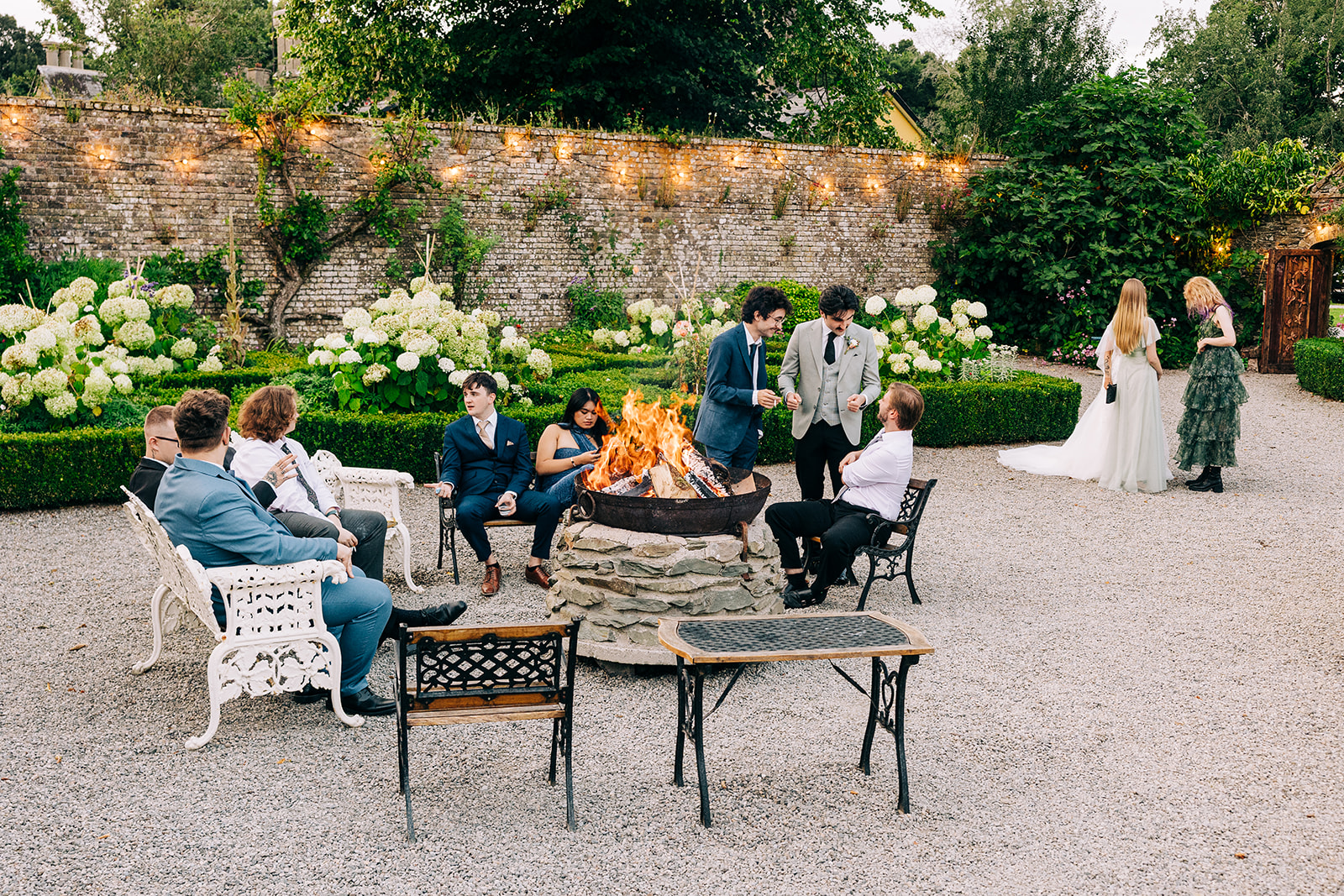 Magdalena & Ronan | Martinstown House wedding guest relaxing by the stone fire pit in the walled garden at Martinstown House in the evening